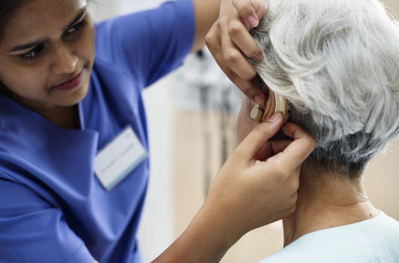 Woman having her hearing aids adjusted by a medical professional.