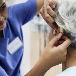 Woman having her hearing aids adjusted by a medical professional.
