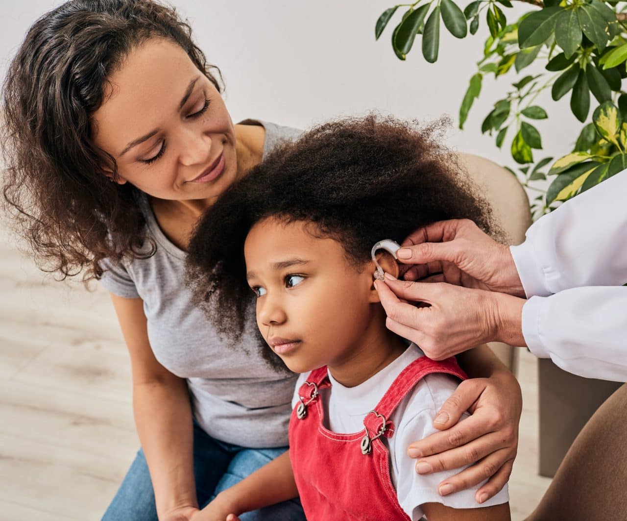 Young girl getting her hearing aid fitted with her mother by her side.