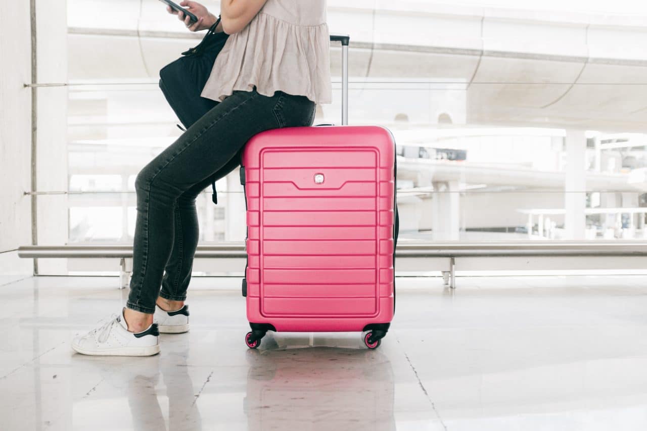 Woman sitting on her luggage as she waits in the airport.