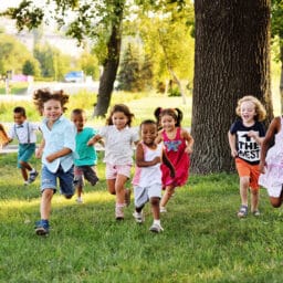 A group of happy children of boys and girls run in the Park on the grass on a Sunny summer day