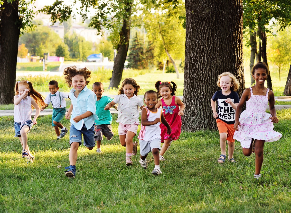 A group of happy children of boys and girls run in the Park on the grass on a Sunny summer day.