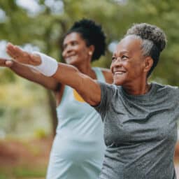 Two senior women doing yoga together in the park