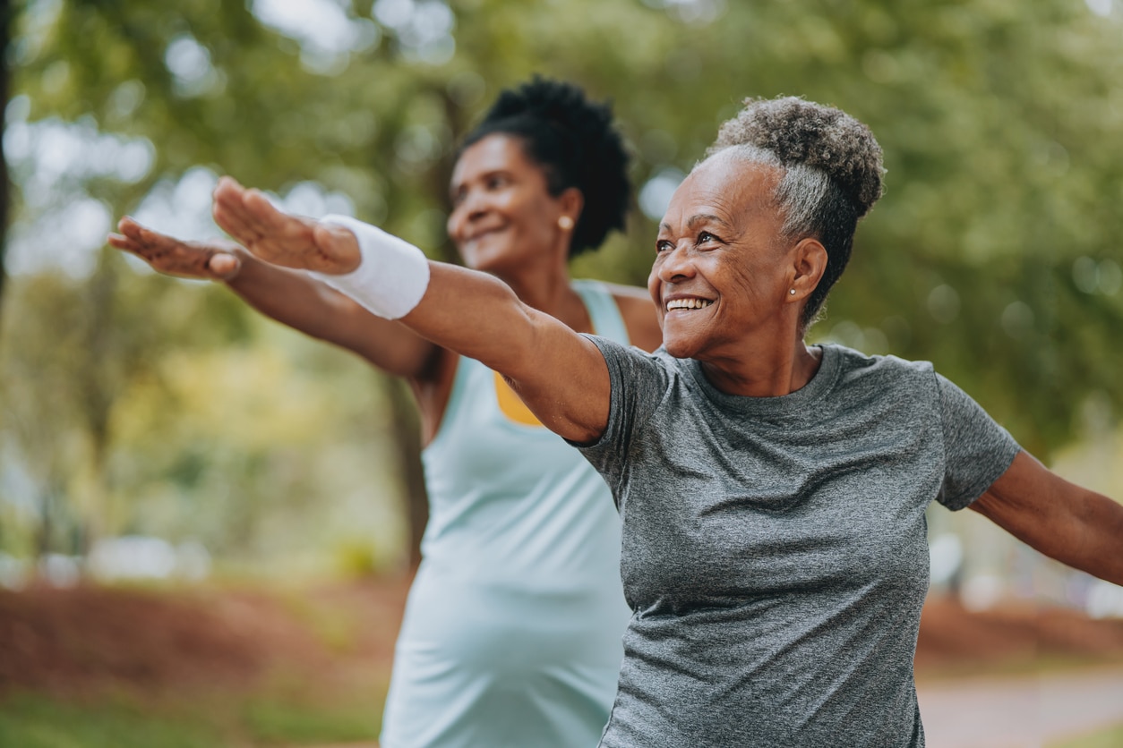 Two senior women doing yoga together in the park.