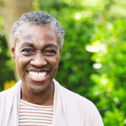 Smiling senior woman against tree background